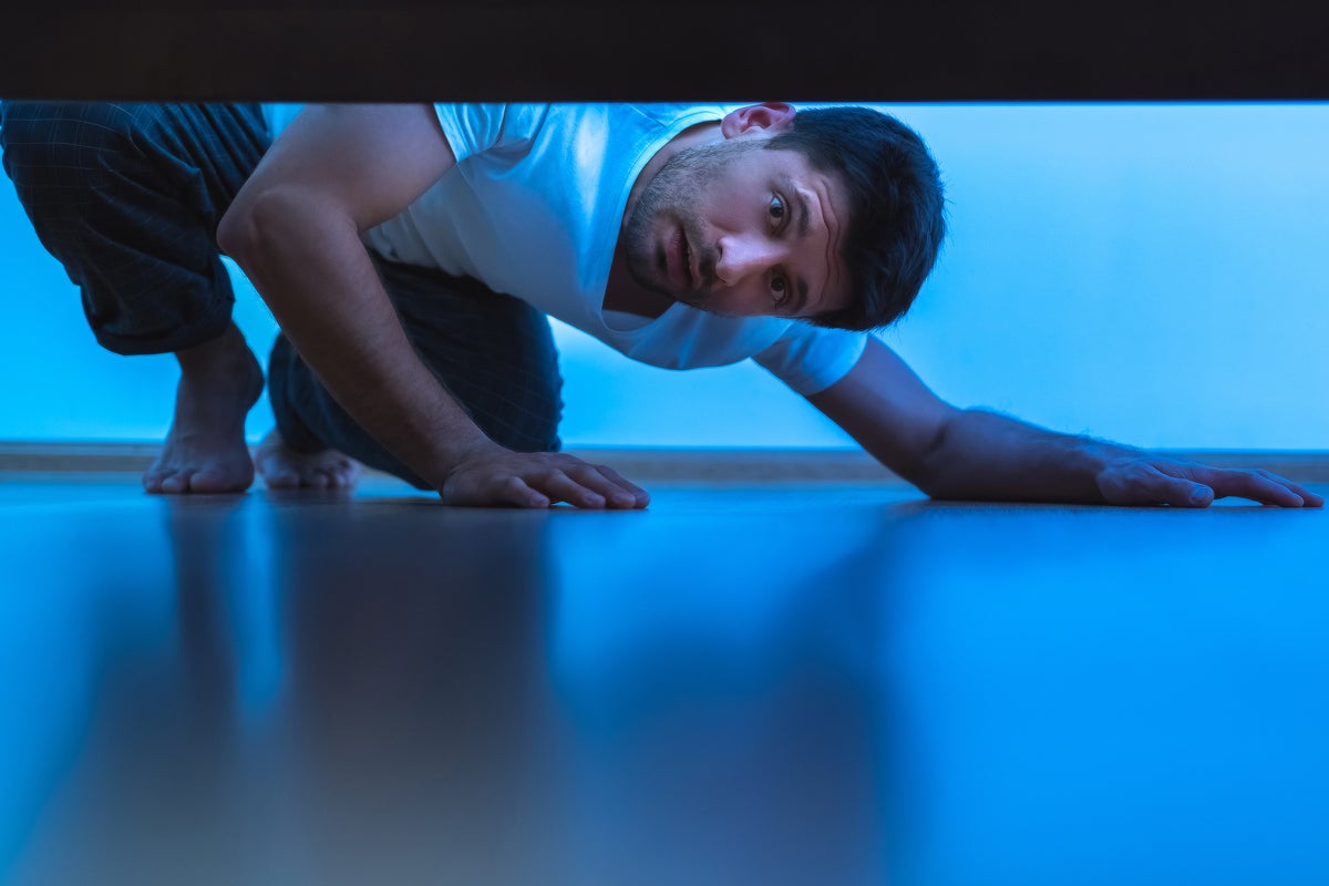 man looking under bed hiding looking for something uncovered by artem peretiatko getty